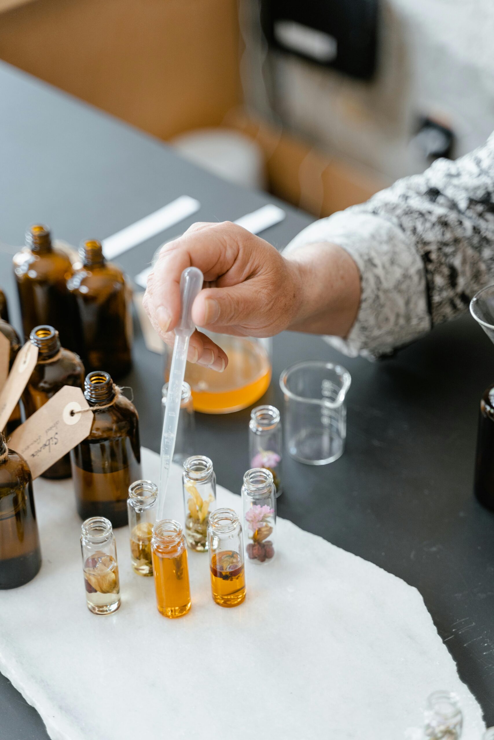 A person blending various natural essential oils in small bottles for aromatherapy.